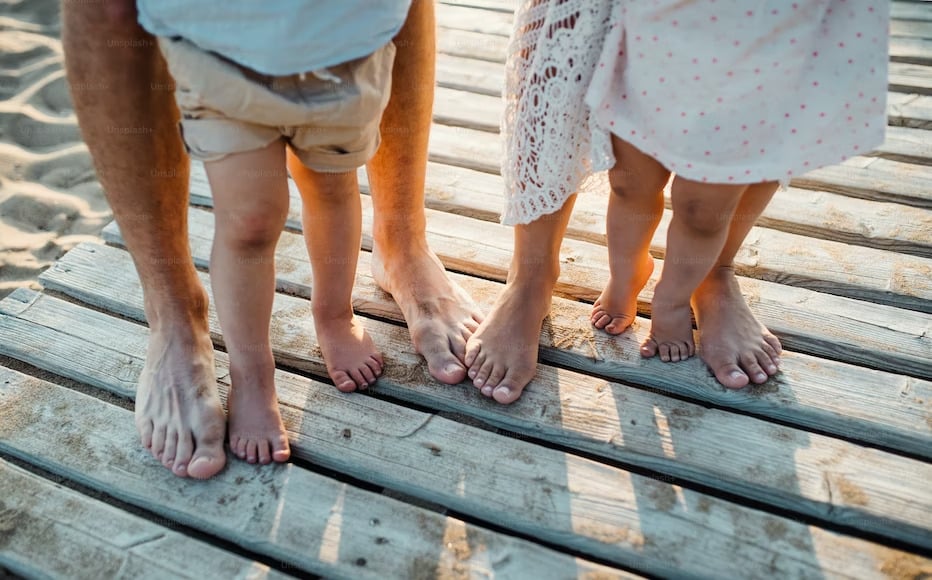 Pieds de famille s'enfonçant dans le sable doux de Normandie, symbole de détente et de bonheur