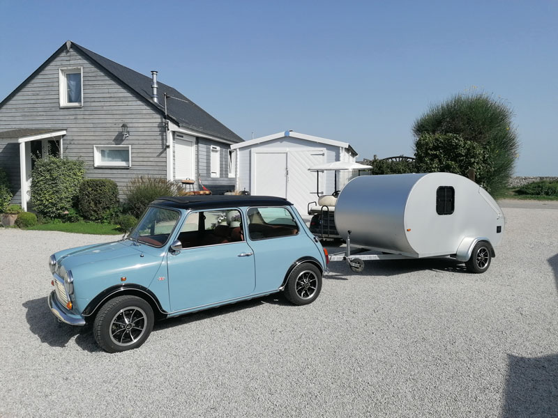 Une caravane vintage admirablement restaurée, entourée par la nature luxuriante du camping La Baie des Veys à Sainte-Marie-du-Mont.