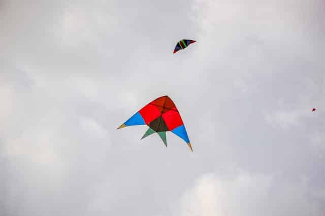 cerf volant Deux enfants rient en faisant voler un grand cerf-volant multicolore sur l'immense plage de sable fin d'Utah Beach, avec leurs parents en arrière-plan. Scène de vacances en famille en Normandie.